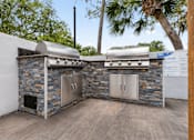 Thumbnail 7 of 28 - A stone wall with a grill and a wooden floor at Epic Apartments , Florida