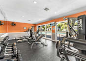 Thumbnail 13 of 28 - A gym with orange walls and a variety of equipment. at Epic Apartments , Daytona Beach, FL, 32114