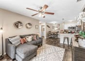 Thumbnail 23 of 28 - A living room with a grey couch and a ceiling fan. at Epic Apartments , Apartments, Daytona Beach, FL