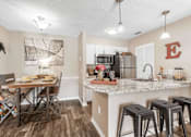 Thumbnail 27 of 28 - A kitchen with a table and chairs in the foreground and a refrigerator with a letter E on it in the background. at Epic Apartments , Daytona Beach, FL, 32114