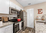 Thumbnail 25 of 28 - A kitchen with a black stove top oven and a black microwave above it at Epic Apartments , Daytona Beach, Florida