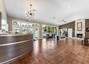 Thumbnail 15 of 28 - A reception area with a brown tile floor and a chandelier hanging from the ceiling. at Epic Apartments , Daytona Beach, Florida