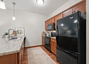 Thumbnail 6 of 37 - Kitchen with granite countertops and black appliances at The Estates at Arbor Oaks Apartments, Minnesota, 55304