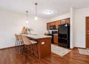 Thumbnail 7 of 37 - Kitchen with island seating and black appliances at The Estates at Arbor Oaks Apartments, Andover, MN 55304