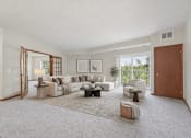 Thumbnail 3 of 37 - Living room with sectional sofa and balcony access at The Estates at Arbor Oaks Apartments, Minnesota