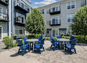 Thumbnail 6 of 24 - A patio with a table and chairs in front of apartment buildings.
