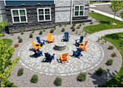 Thumbnail 5 of 24 - A stone building with a circular patio and chairs around a fire pit.