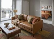 Thumbnail 21 of 26 - Modern living room with leather sofa and balcony view at Hello Apartments, Minneapolis