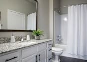 Thumbnail 25 of 26 - Modern bathroom with granite countertop and white cabinetry at Hello Apartments, Minneapolis, MN