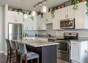 Thumbnail 23 of 26 - Modern kitchen with granite island and pendant lighting at Hello Apartments, Minneapolis