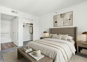 Thumbnail 6 of 10 - A bedroom with a large bed and a nightstand with a lamp.