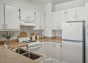 Thumbnail 9 of 12 - A kitchen with white cabinets and appliances.