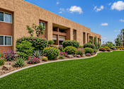Thumbnail 4 of 23 - A building with a green lawn in front of it.