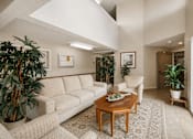 Thumbnail 13 of 23 - A living room with a couch, chair, and potted plants.