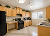 Thumbnail 15 of 23 - A kitchen with wooden cabinets and black appliances.