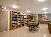 Thumbnail 16 of 23 - A room with a long bookshelf and a table with chairs.