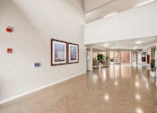 Thumbnail 20 of 23 - A hallway with a tiled floor and white walls, with two framed pictures on the wall.