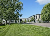 Thumbnail 1 of 25 - A grassy area in front of a building with trees on the sides at Aster Meadow, Vadnais Heights, MN, 55127