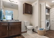 Thumbnail 25 of 25 - A bathroom with a white toilet, a wooden cabinet, and a washing machine.