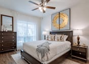 Thumbnail 22 of 25 - A bedroom with a large bed, a dresser, and a ceiling fan.