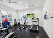 Thumbnail 15 of 25 - A spacious gym with a variety of equipment including treadmills, weights, and a television.