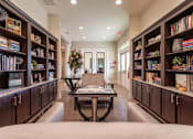 Thumbnail 7 of 25 - A living room with a coffee table in the middle and bookshelves on both sides.
