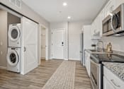 Thumbnail 29 of 41 - Kitchen with stacked washer dryer and barn door at The Hendrickson Apartments, Minnesota