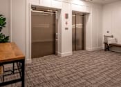 Thumbnail 21 of 41 - Elevator lobby with decorative lighting and seating at The Hendrickson Apartments, Falcon Heights, Minnesota