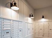 Thumbnail 22 of 41 - Mail room with wall mounted mailboxes and overhead lighting at The Hendrickson Apartments, Falcon Heights