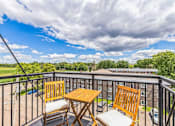 Thumbnail 33 of 41 - Private balcony with outdoor dining furniture and skyline views at The Hendrickson Apartments, Falcon Heights, MN 55113