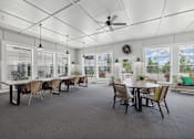 Thumbnail 19 of 41 - Community dining area with wicker chairs and large windows at The Hendrickson Apartments, Falcon Heights, Minnesota