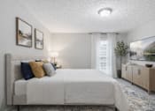 Thumbnail 13 of 16 - A bedroom with a large bed, a nightstand with a lamp, and a painting on the wall.