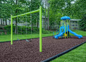 Thumbnail 6 of 16 - A playground with a blue slide and a green swing set.