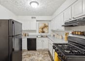 Thumbnail 8 of 15 - A kitchen with black appliances and white cabinets at Emerald Pointe, Riverdale, GA