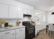 Thumbnail 9 of 15 - A kitchen with a black stove top oven and white cabinets at Emerald Pointe, Riverdale, GA