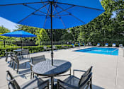 Thumbnail 2 of 15 - A blue umbrella is over a table with chairs around it at Emerald Pointe, Riverdale, GA