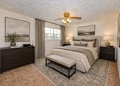 Thumbnail 16 of 17 - A bedroom with a large bed, a bench, and a ceiling fan.