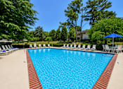 Thumbnail 7 of 17 - A large swimming pool surrounded by trees and chairs.