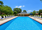 Thumbnail 8 of 17 - A large blue swimming pool with white lounge chairs on either side.