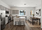 Thumbnail 7 of 16 - A modern kitchen with a dining table and chairs.