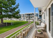 Thumbnail 2 of 26 - Private balcony with seating and courtyard views at Park Station Apartments, Midvale, Utah