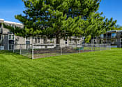 Thumbnail 4 of 26 - Fenced dog with large tree at Park Station Apartments, Utah