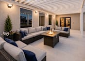 Thumbnail 5 of 26 - Covered patio with sectional seating and fire table at Park Station Apartments, Utah, 84047