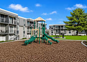 Thumbnail 9 of 26 - Playground area with apartments and green space at Park Station Apartments, Midvale, Utah