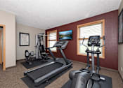 Thumbnail 12 of 23 - A home gym with a treadmill, elliptical trainer and a stationary bike.