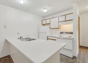 Thumbnail 38 of 38 - A white kitchen with a sink and a refrigerator.