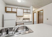 Thumbnail 29 of 38 - A kitchen with a white fridge, sink, and countertops.