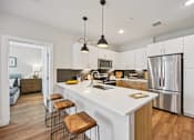 Thumbnail 29 of 39 - Modern kitchen with white island and pendant lights at Sequel Homes Apartments, Colorado, 80110