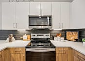 Thumbnail 31 of 39 - Kitchen with white cabinets and stainless steel range at Sequel Homes Apartments, Englewood, CO