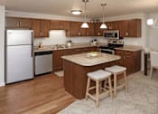 Thumbnail 15 of 18 - Modern kitchen with island and wood cabinetry at Cypress Court Apartments, St Cloud